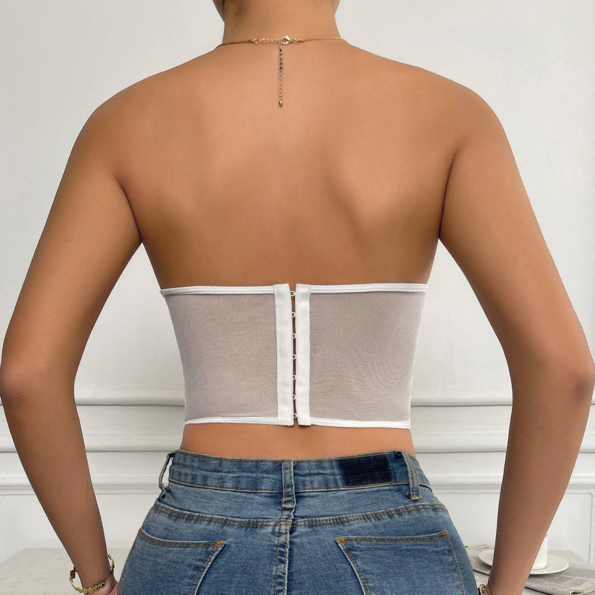 Back view of sheer white corset with hook-and-eye closure.