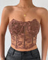 Model wears brown strapless corset with floral embroidery and sheer design.
