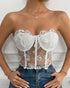 Front view of woman in white strapless corset with rose embroidery and boning.
