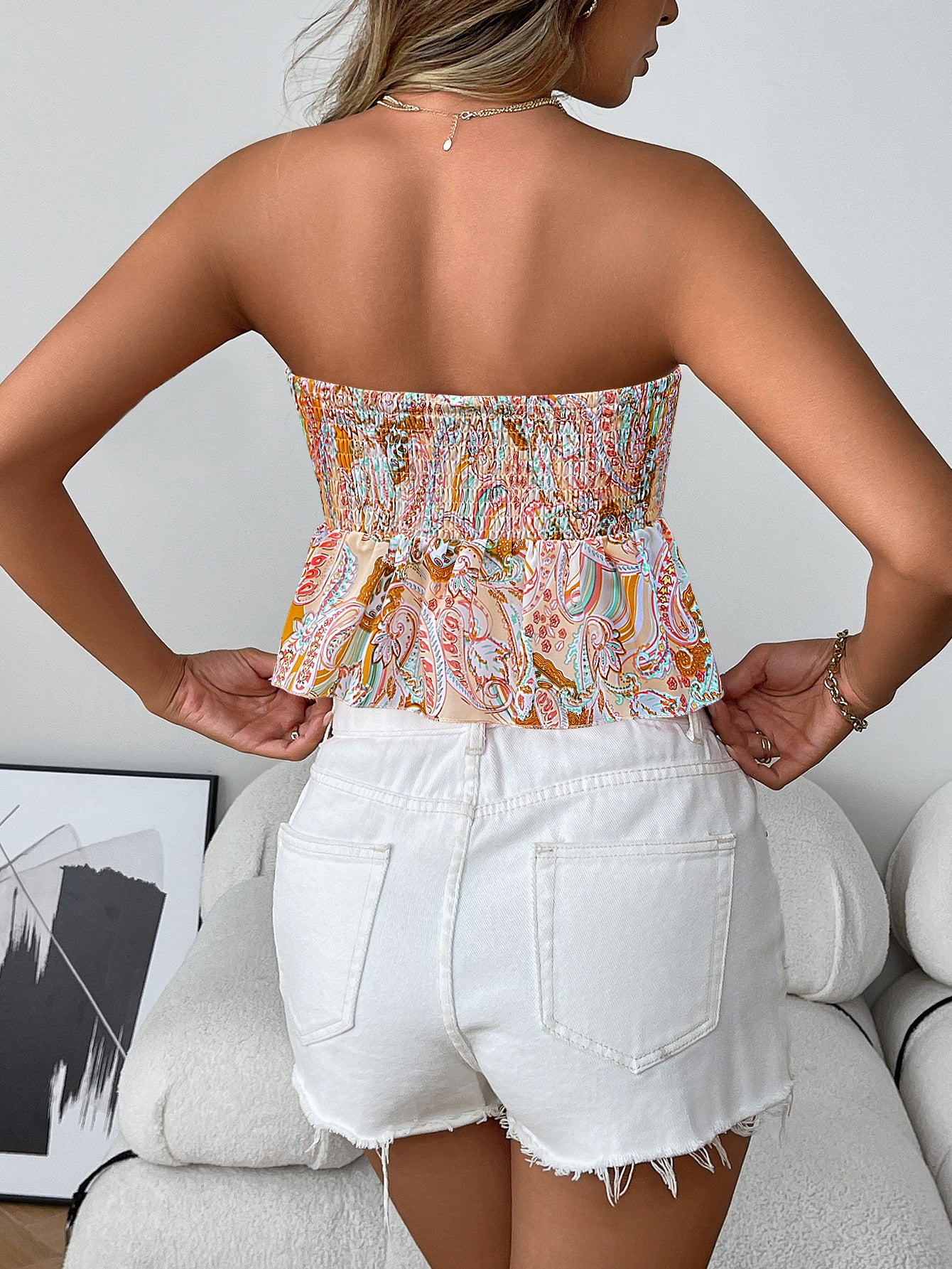 Back view of woman wearing apricot smocked boho strapless tube top with flare hem in paisley print