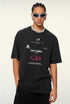 Model poses in black tee with printed phrases and layered necklace