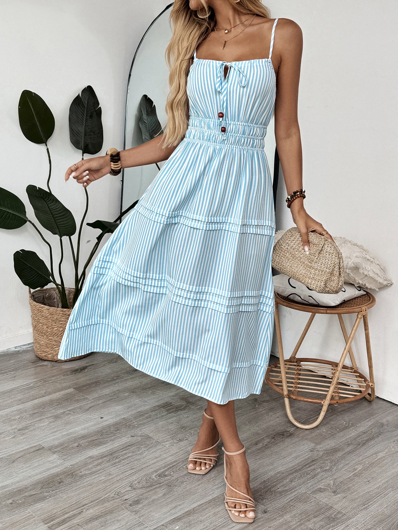 Spinning pose in striped cami dress with smocked waist and decorative buttons.