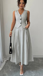 Front view of striped sleeveless vest and skirt set styled with a black handbag