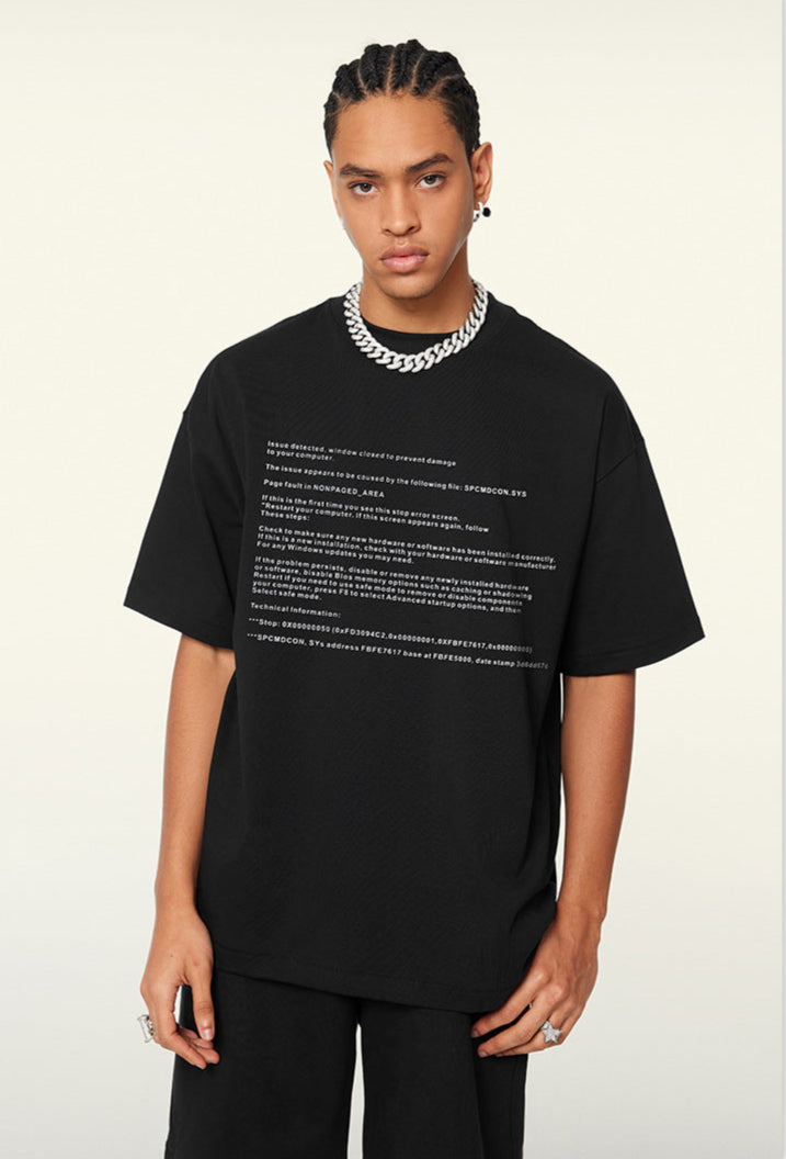 Model poses in black tee with tech-style error text across the chest.
