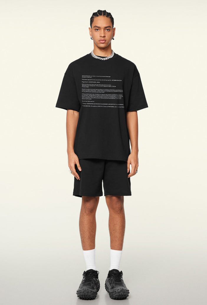 Model wears black system crash tee with matching shorts and chunky sneakers.