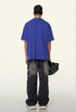 Model shows back of plain academy blue tee with frayed black pants.