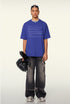 Model wears academy blue crash report tee with distressed black cargo pants.