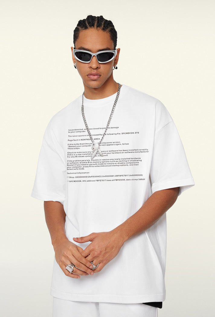 Close-up of white oversized tee with black crash text and silver chain.