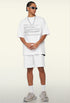 Model angles body in white tee with printed text and layered accessories.