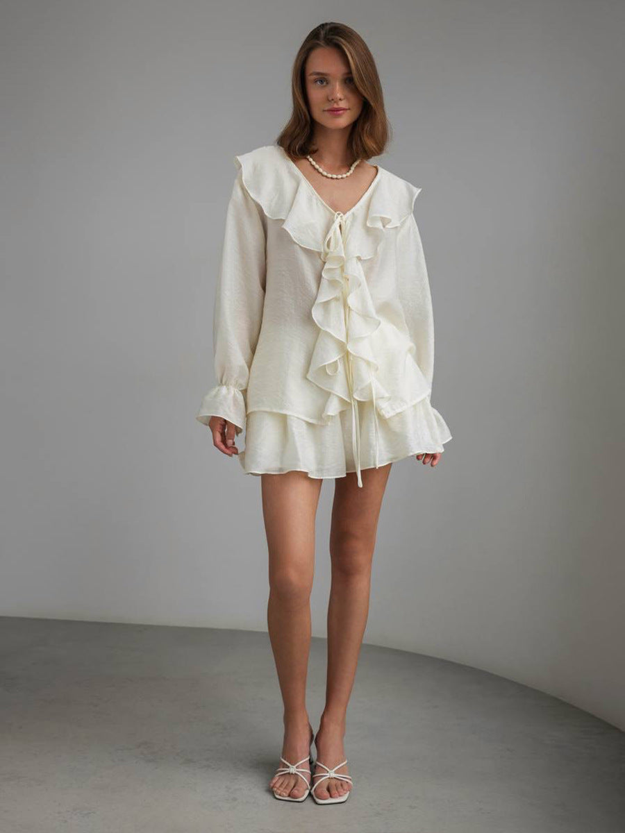 Woman wearing a beige ruffled 2-piece set against a plain background