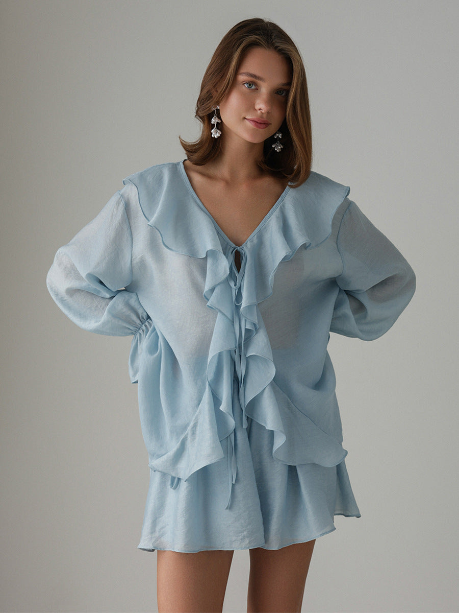 Woman wearing a light blue ruffled blouse set against a gray background