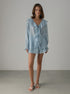 Woman wearing a light blue ruffled blouse and shorts set against a plain background