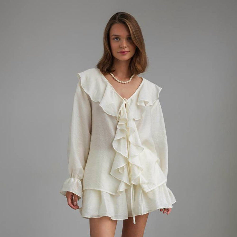 Woman wearing a beige ruffled 2-piece set against a gray background