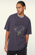 Model poses in purple "Terrible Beauty" tee looking left.