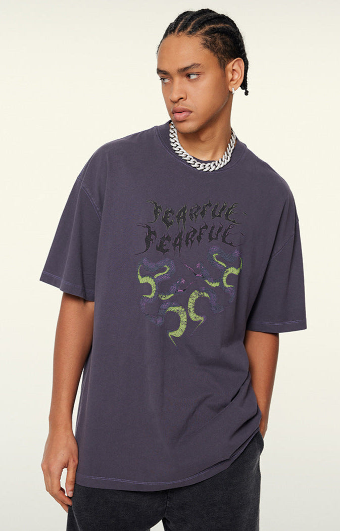 Model poses in purple "Terrible Beauty" tee looking left.