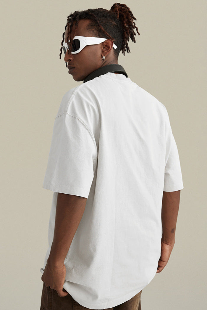 Rear view of white "Terrible Beauty" tee worn with headphones and sunglasses.
