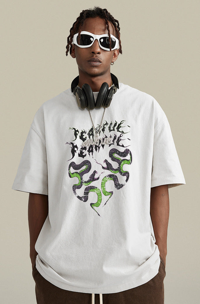 Close-up of white "Terrible Beauty" tee with bold graphic and headphones.
