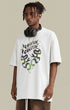 Model in white "Terrible Beauty" tee facing left with headphones around neck.