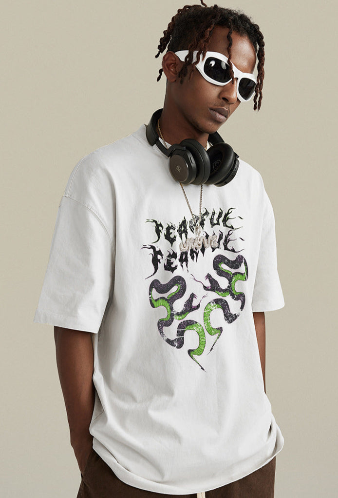 Model in white tee with white sunglasses and snake-heart graphic.