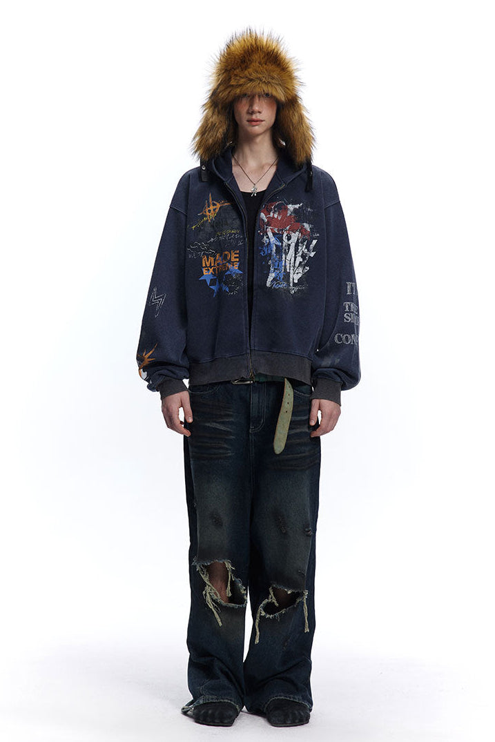 Navy oversized graffiti zip-up hoodie styled with distressed wide-leg jeans and a fur hat.
