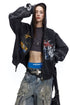 Close front view of charcoal zip-up hoodie showing hood, sleeve, and chest graphics.