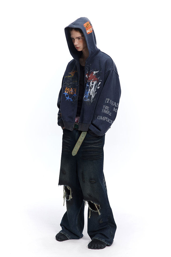 Three-quarter view of navy graffiti zip-up hoodie worn with the hood up and dark denim.
