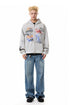 Full-length front view of heather gray graphic zip-up hoodie and relaxed denim.