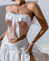 Side view of pink strapless corset with white bow and ruffle trim, styled with ruched white skirt.