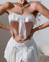 Front view of pink velvet corset top with oversized white bow and ruffled neckline, styled with white mini skirt.