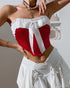 Front view of red strapless corset with bold white bow and gathered trim, styled for a festive look.
