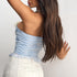 Back view of a light blue floral lace corset top with lace trim, worn with a high-waisted white skirt.