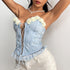 Woman stretching in a light blue floral corset top with lace trim and white shorts.