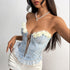 Woman leaning forward in a light blue floral corset top with yellow flower details and lace-up front.