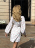 Back view of white mini dress with floral print and long sleeves.