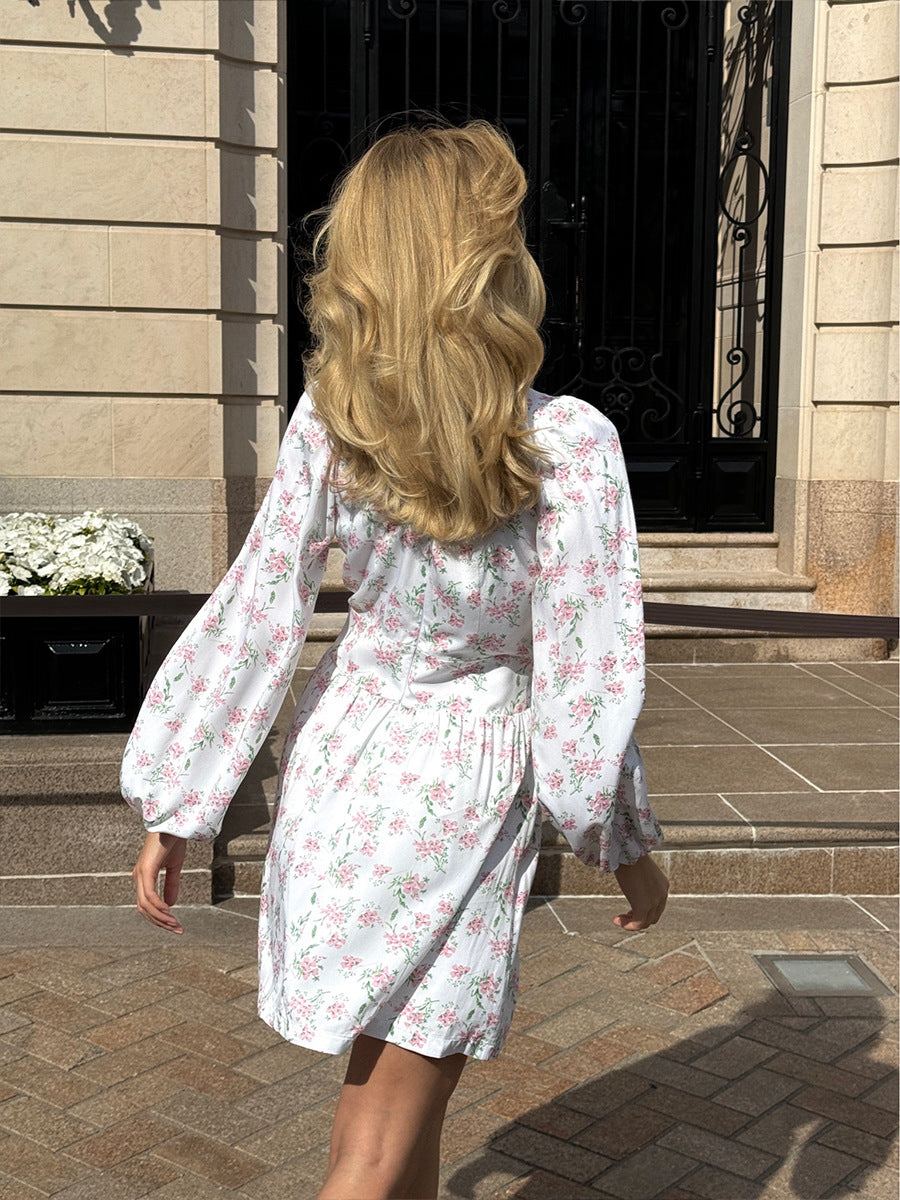 Back view of white mini dress with floral print and long sleeves.