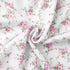 Close-up of white fabric with pink floral print in soft folds.