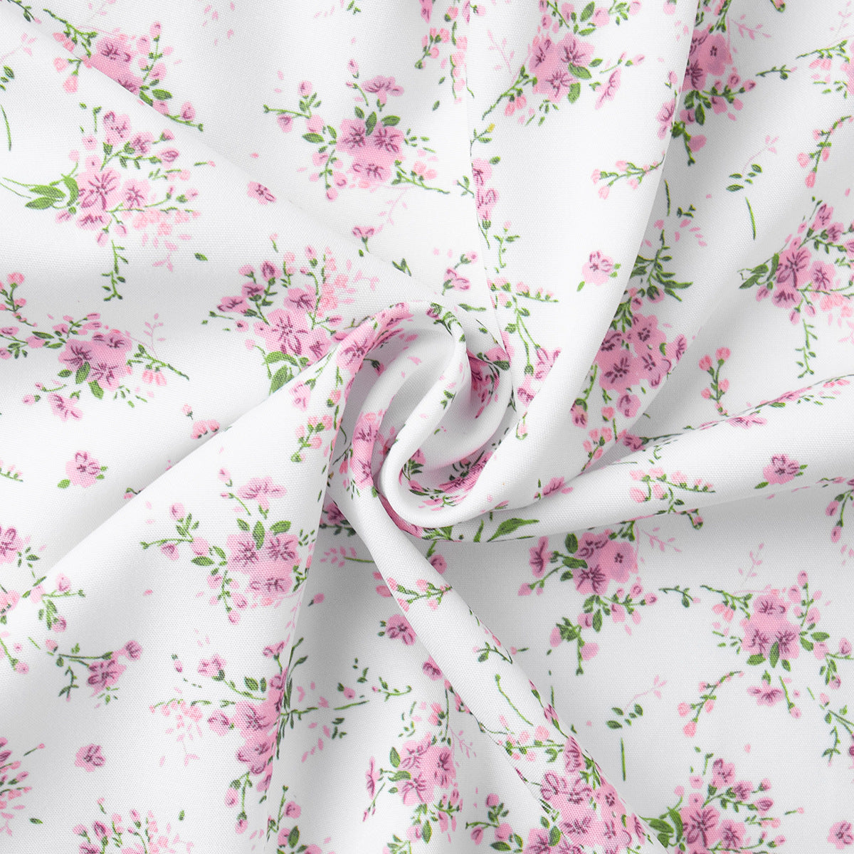 Close-up of white fabric with pink floral print in soft folds.