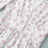 Close-up of waist and pearl button details on white floral mini dress