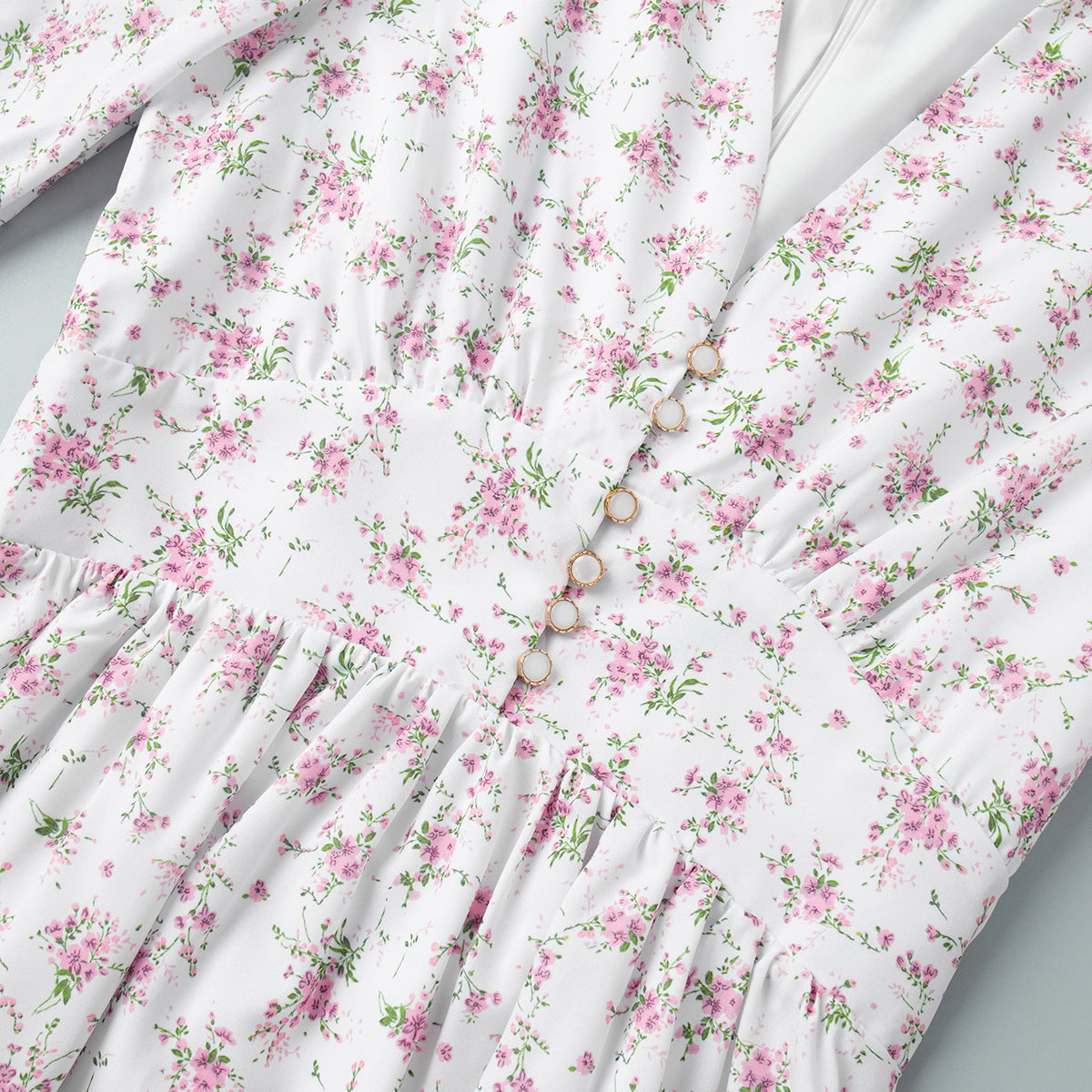 Close-up of waist and pearl button details on white floral mini dress
