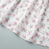 Hemline and floral fabric detail of white v-neck mini dress