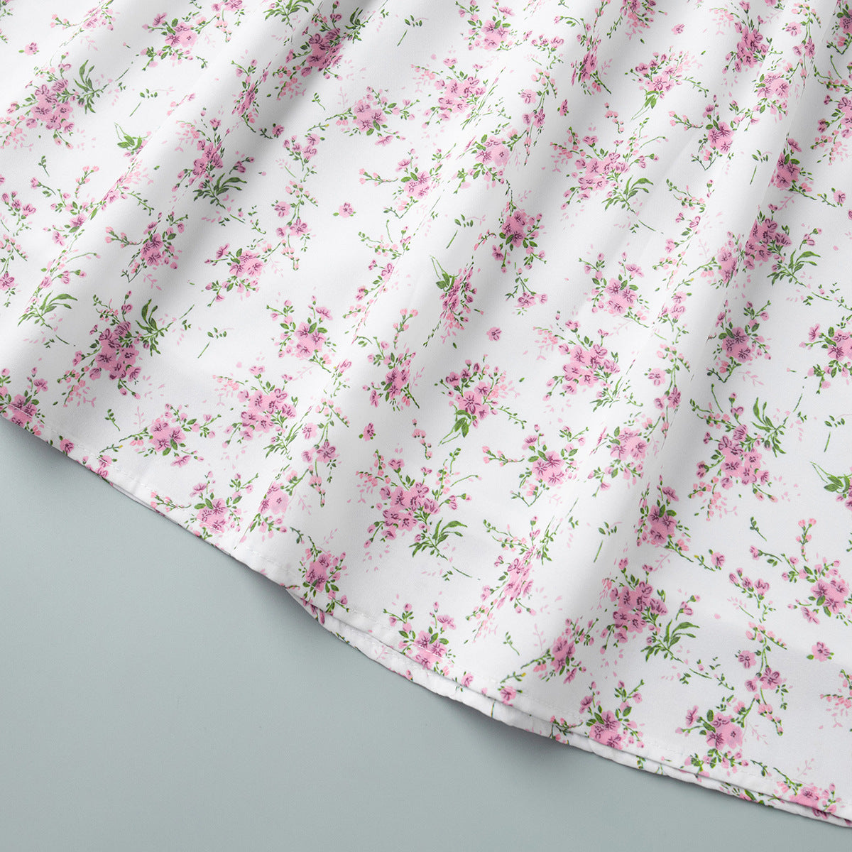 Hemline and floral fabric detail of white v-neck mini dress