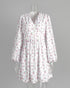White floral mini dress with v-neck and balloon sleeves on clear mannequin.