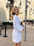 Side view of white floral mini dress worn by woman outdoors.