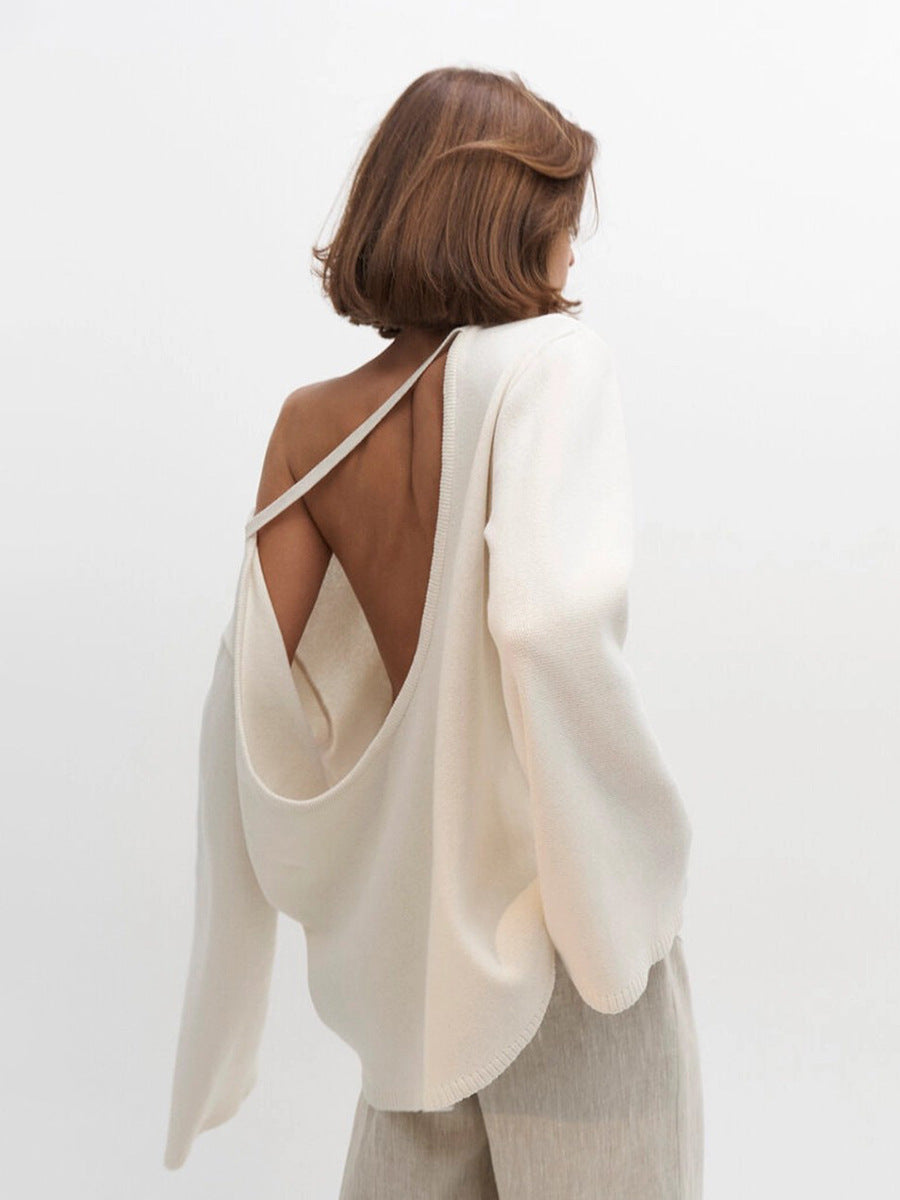 Woman wearing a white open-back knit sweater with a plain background