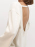 Close view of white backless knit sweater on a plain background