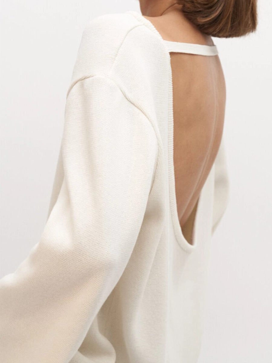 Close view of white backless knit sweater on a plain background