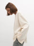 Side angle of woman wearing white backless knit sweater