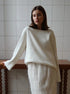 Woman styling white backless knit sweater with skirt indoors