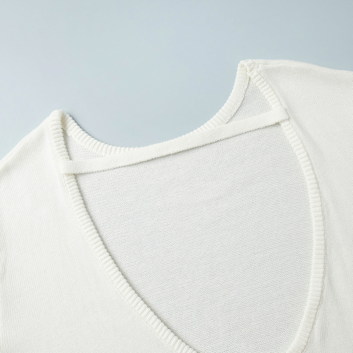 Strap detail close-up of white backless knit sweater
