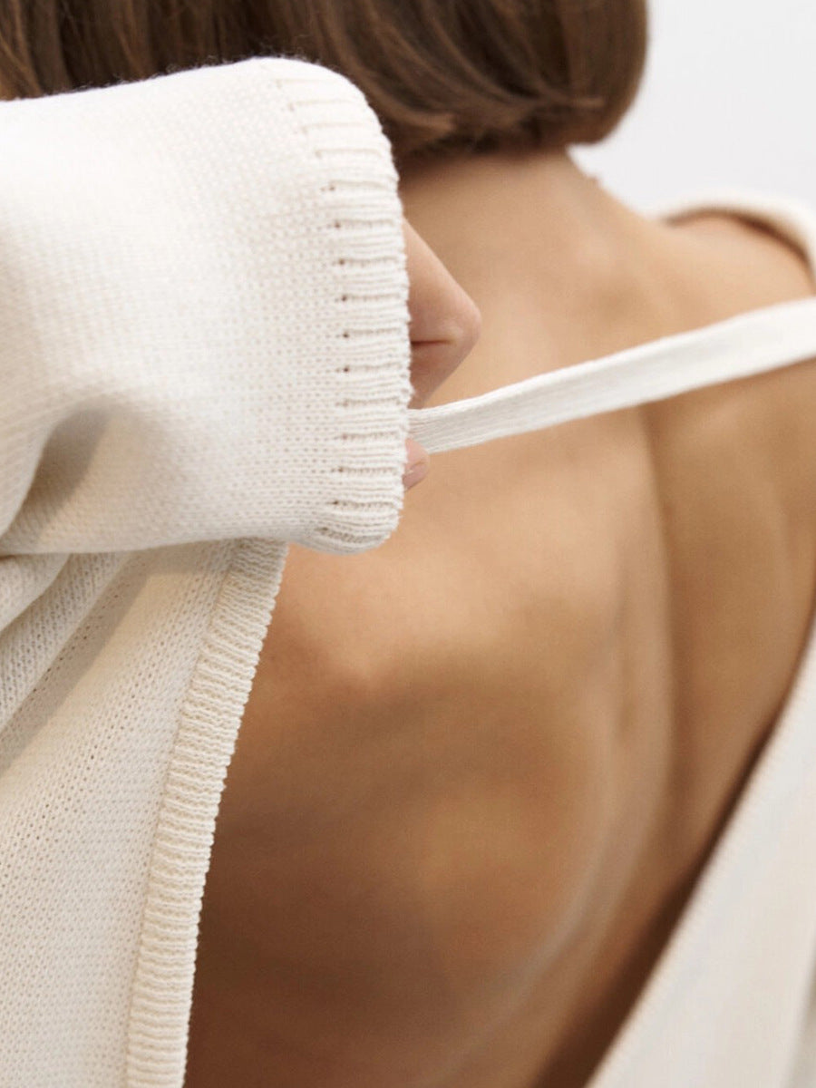 Strap detail close-up of white backless knit sweater
